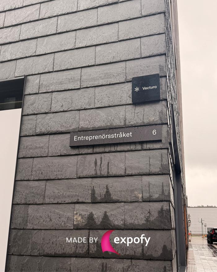Två monterade skyltar på stenfasad – en företagsskylt för Vectura och en adressskylt med texten Entreprenörsstråket 6.
