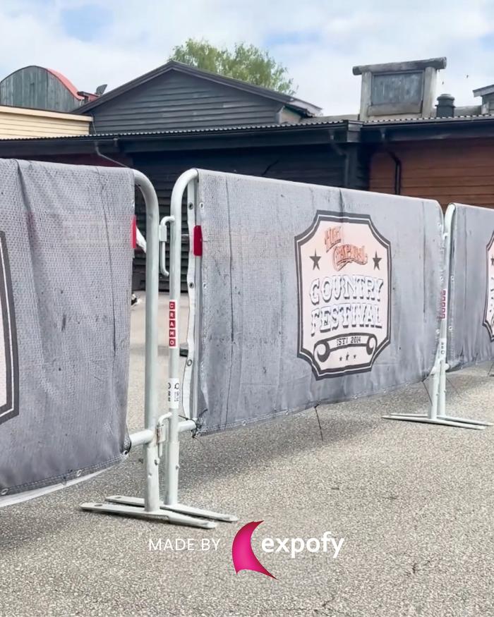 Tryckt meshbanner med Country Festival-logotyp, monterad på avspärrningsstängsel utomhus.