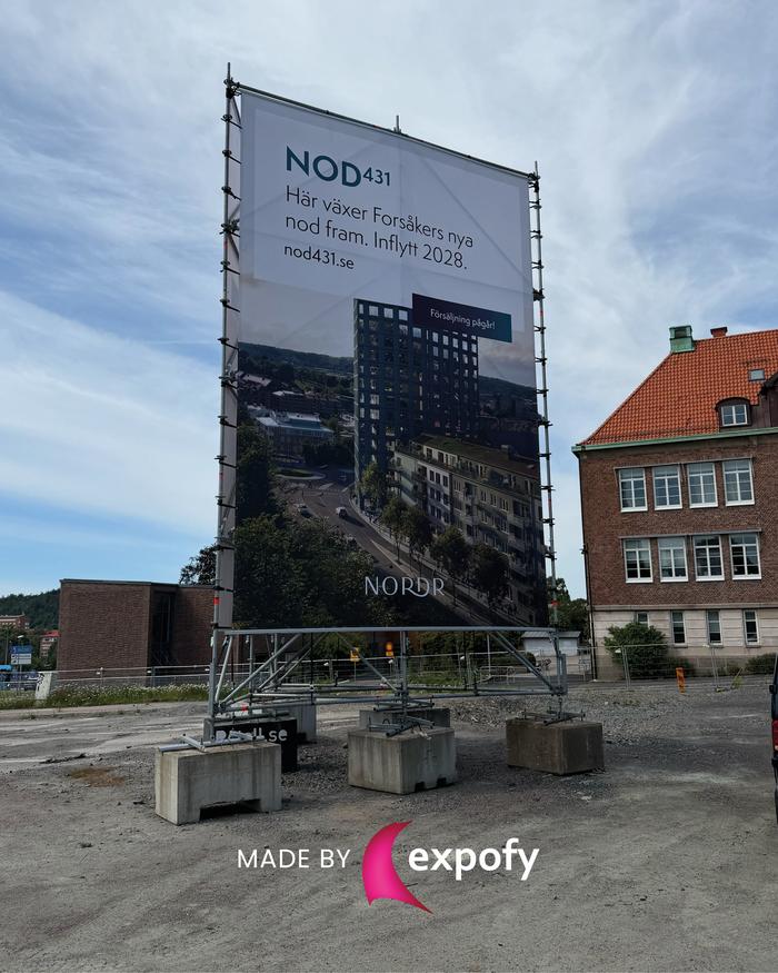 Stor tygvepa på fristående byggnadsställning visar NOD431-projekt med text och byggnadsbild, placerad på en byggarbetsplats.